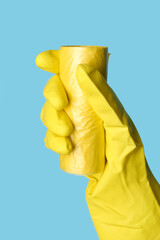 Hand in rubber glove with roll of garbage bags on blue background