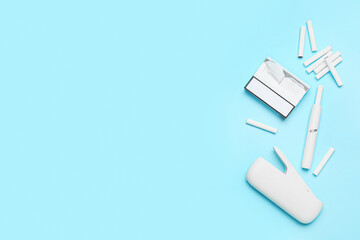 Modern electronic cigar, pack and sticks on blue background
