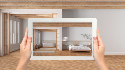 Fototapeta na wymiar Augmented reality concept. Hand holding tablet with AR application used to simulate furniture and design products in empty wooden interior, minimal bedroom and bathroom