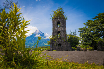 volcano in eruption next to old bell tower demolished by lava