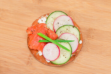Crispy Cracker Sandwich with Salmon, Cucumber, Radish, Cottage Cheese and Green Onions on Bamboo Cutting Board. Easy Breakfast. Quick and Healthy Sandwiches. Crispbread with Tasty Filling