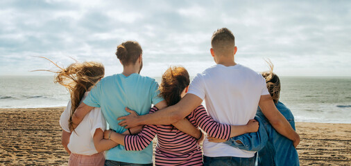 Millennial diverse people in casual hugging, enjoy vacation, freedom on sea beach at weekend outdoor