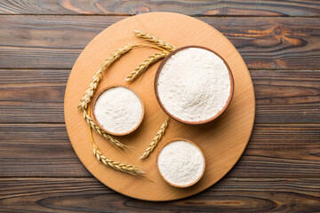 Flat lay of Wheat flour in wooden bowl with wheat spikelets on colored background. world wheat crisis