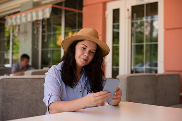 Stylish woman in hat with smartphone outside,making video call and smile.