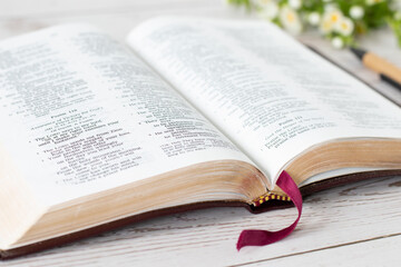 Open holy bible book with flowers and pen on wooden table. A close-up, selective focus. Christian...