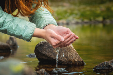 palms touch the water in the pond. Water in woman's hands. Woman takes clean water in her hands...
