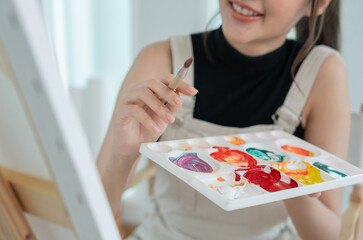 Fototapeta premium Professional female artist girl use paintbrush in abstract art for create masterpiece. painter paint with watercolors or oil in studio house. beautiful woman enjoy painting as hobby. work recreation