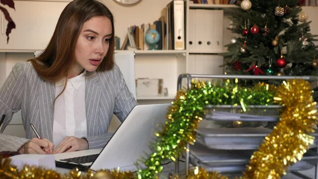 Female office worker sitting at desk and doing paperwork during Christmastime.