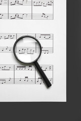 Magnifier with music sheet on black and white background