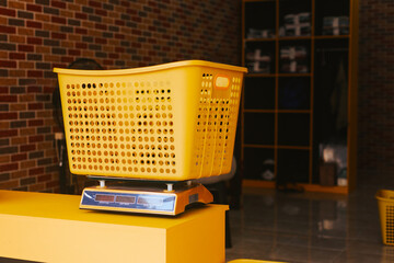 A yellow plastic laundry basket is on the scales. Laundry room for washing clothes