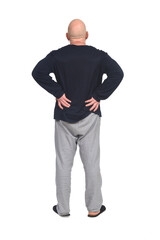 back view of a man in pajamas arms akimbo on white background