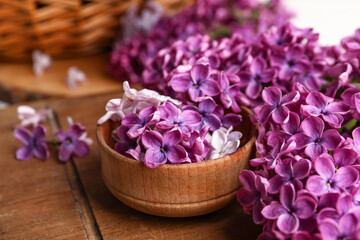 Bowl of beautiful fragrant lilac flowers on wooden table