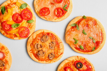 Different tasty mini pizzas on grey background