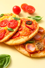 Different tasty mini pizzas on yellow background