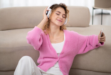 Beautiful Young Female In Headphones Listening Music With Closed Eyes At Home