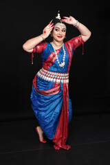 Woman performing Odissi dance in colorful costume. Indian classical dance forms.