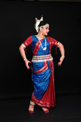 Fototapeta premium Woman performing Odissi dance in colorful costume. Indian classical dance forms.