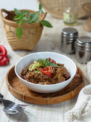 Tumis Daging Sapi Mercon or Stir fry or saute of beef with onion, red cayenne pepper and other herb and seasoning. Serving in white plate on wooden table. Indonesian food, recipe and cuisine