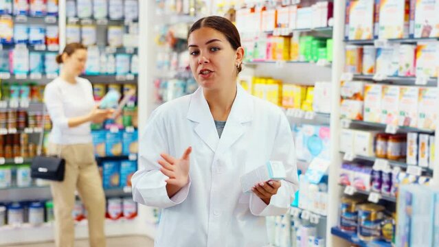 Young female pharmacist posing with remedy in pharmacy. High quality 4k footage