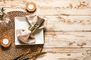 Beautiful table setting with candles and gypsophila flowers on light wooden background