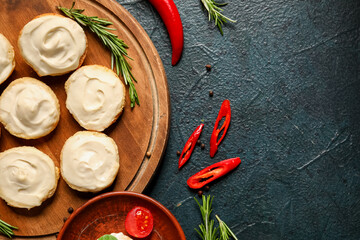 Wooden board of tasty croutons with cream cheese on dark background