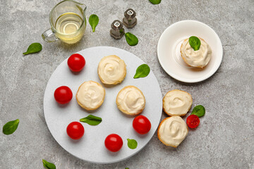 Board and plate of tasty croutons with cream cheese on grey background