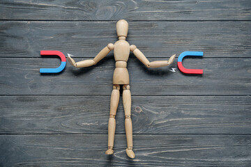 Wooden mannequin with magnets on dark wooden background