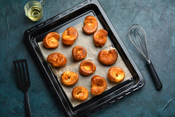Baking tray with tasty Yorkshire pudding on blue background