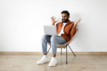 Emotional middle eastern man using laptop and shouting sitting indoor