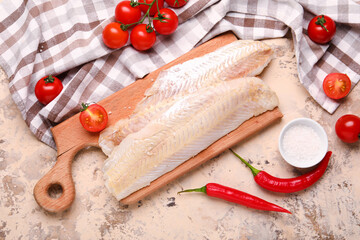 Wooden board with raw codfish fillet and tomatoes on beige background - obrazy, fototapety, plakaty