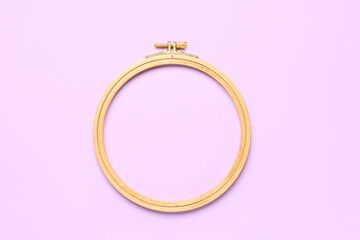 Wooden embroidery hoop on lilac background