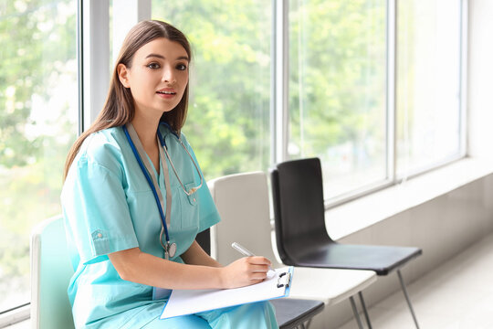 Female medical intern writing in clipboard at hospital