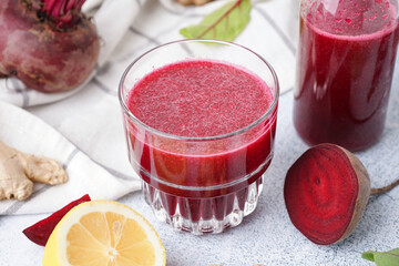 Glass of fresh beetroot juice and ingredients on light background