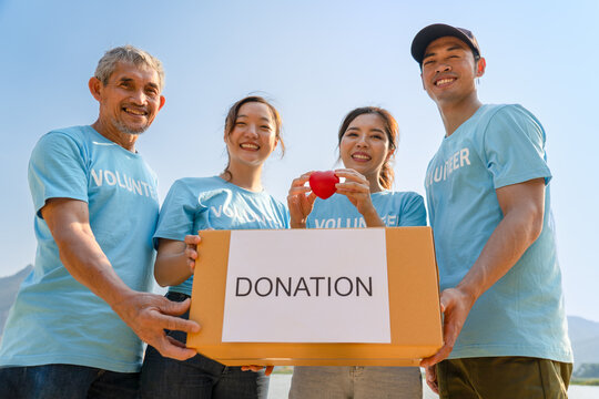group of diverse volunteers carrying donation box and a red heart charitable working together for campaign donations to help underprivileged people by donate food, clothing or support education