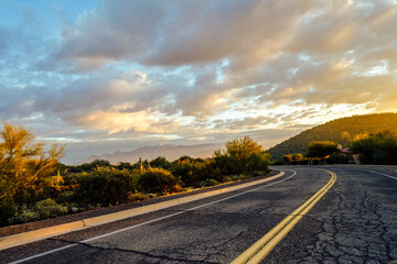 Curvy Road with Yellow Stripes and Sunset with yellow and blue clouds