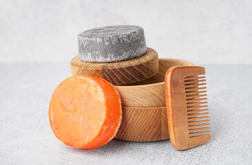 Different handmade solid shampoo and hair comb on light background, closeup