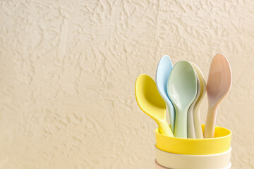 Colorful spoons and cups for baby on white textured background