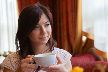 Portrait of a happy young girl in a cafe with a mug in her hand