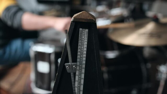 Mechanical metronome for music rhythm and tact measuring working during musician playing music on drums with drumsticks. Classical tool for musicians and song creators