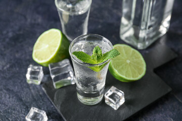 Glass of cold vodka on black background