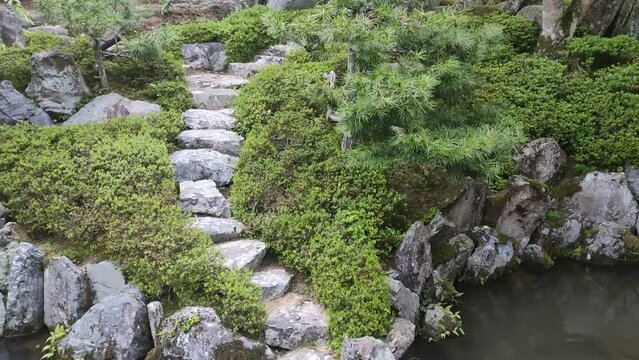 Balade dans un grand jardin japonais, autour d'un grand lac vert transparent, sur une terrasse flottante en pierre, lieu zen et calme, coin détente, beauté de la verdure, naturelle et urbaine,