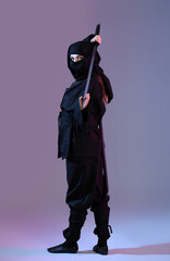 Female ninja with sword on color background