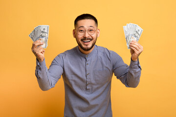 Lucky Winner. Excited Millennial Asian Man Holding Money Cash In Hands