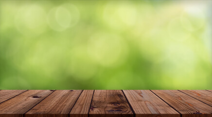 Wood table top on Defocus Bokeh Green Nature background,Abstract blurry light with Empty brown wooden perspective counter,Backdrop Display for Organic Food and Drink,Cosmetic Promotion,Advertising