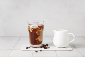 Glass of tasty ice coffee with milk on table