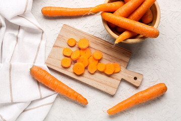 Board with slices and bowl of fresh carrots on white background