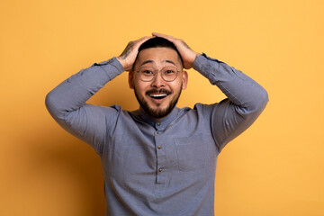 Portrait Of Surprised Aisan Man Touching Head And Opening Mouth In Amazement