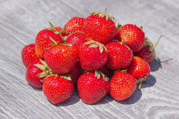 Heap of fresh strawberry on gray wooden table background in rustic style