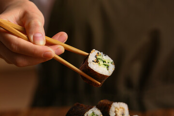 Woman holding chopsticks with tasty maki roll, closeup © Pixel-Shot