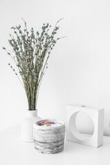 Lavender flowers and candle on table near light wall in room, closeup